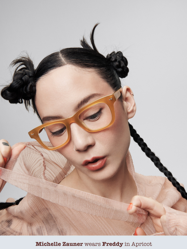 Girl Posing with hands on blouse wearing glasses.