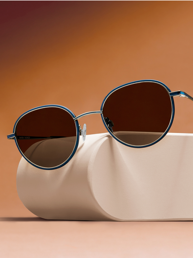 Close up on Henderson frames on top a geometric object against a gradient orange background.