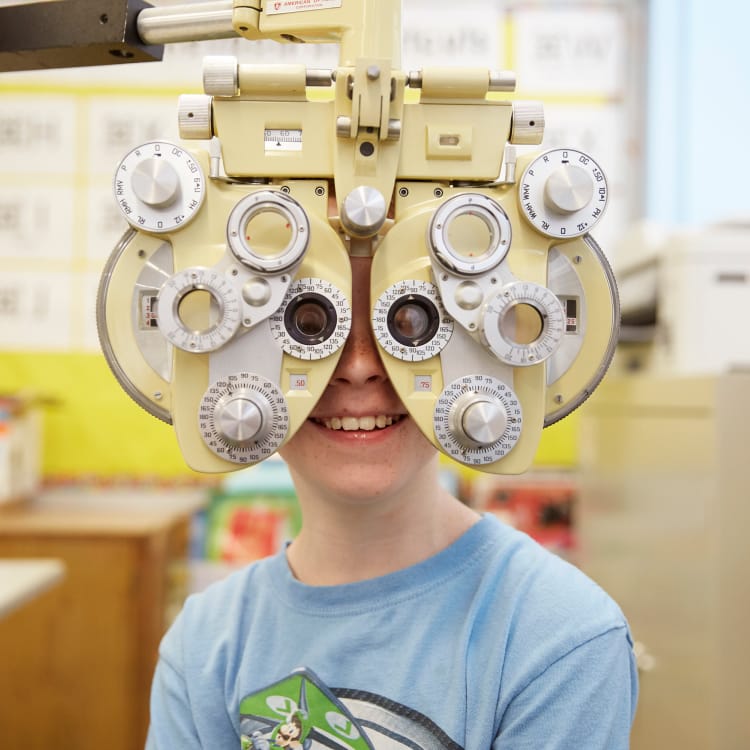 Child with a phoropter during an eye exam.