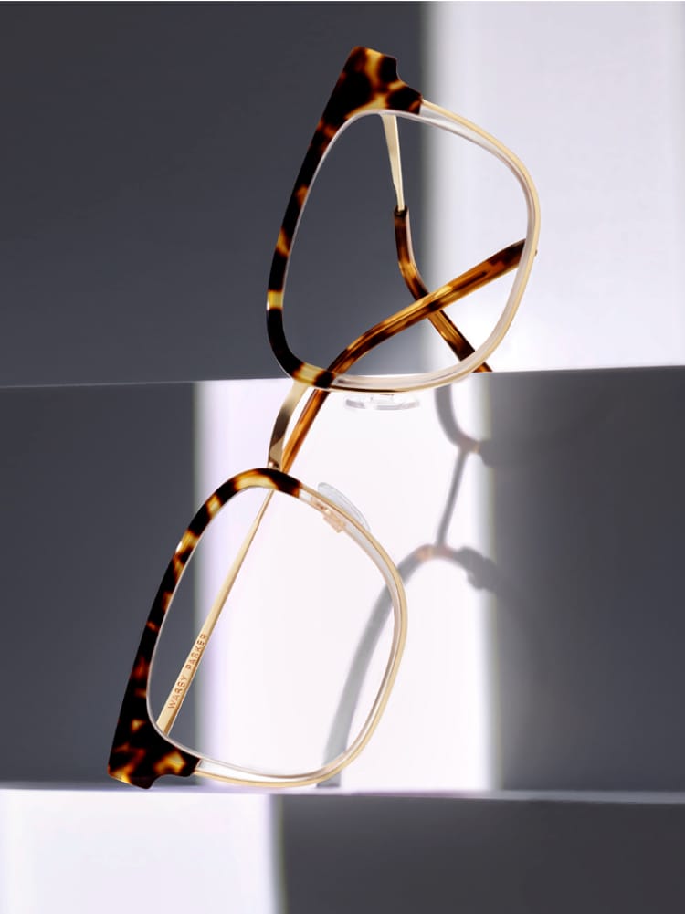 Close up of glasses leaning towards a geometric white piece.