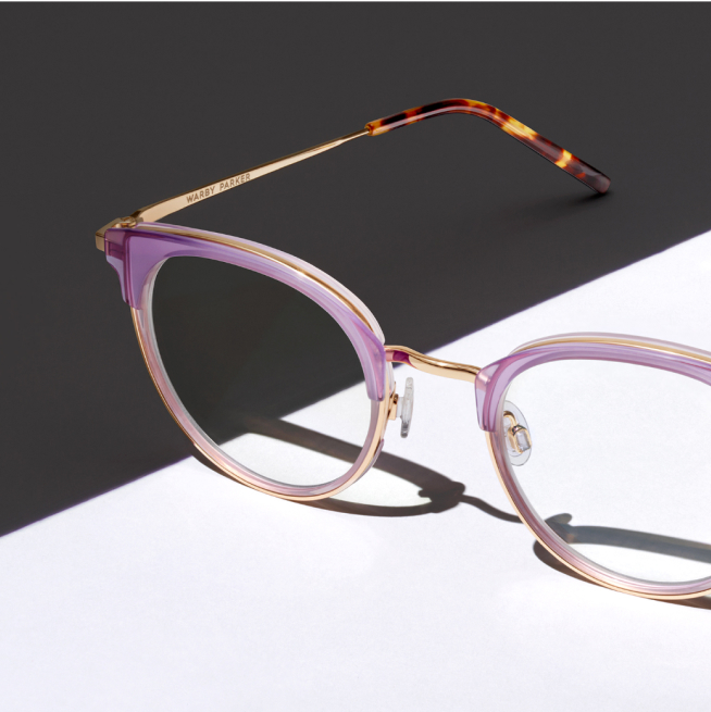 Close up on pink eyeglasses with a Gray and white background.