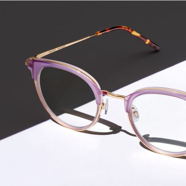 Close up on pink eyeglasses with a Gray and white background.
