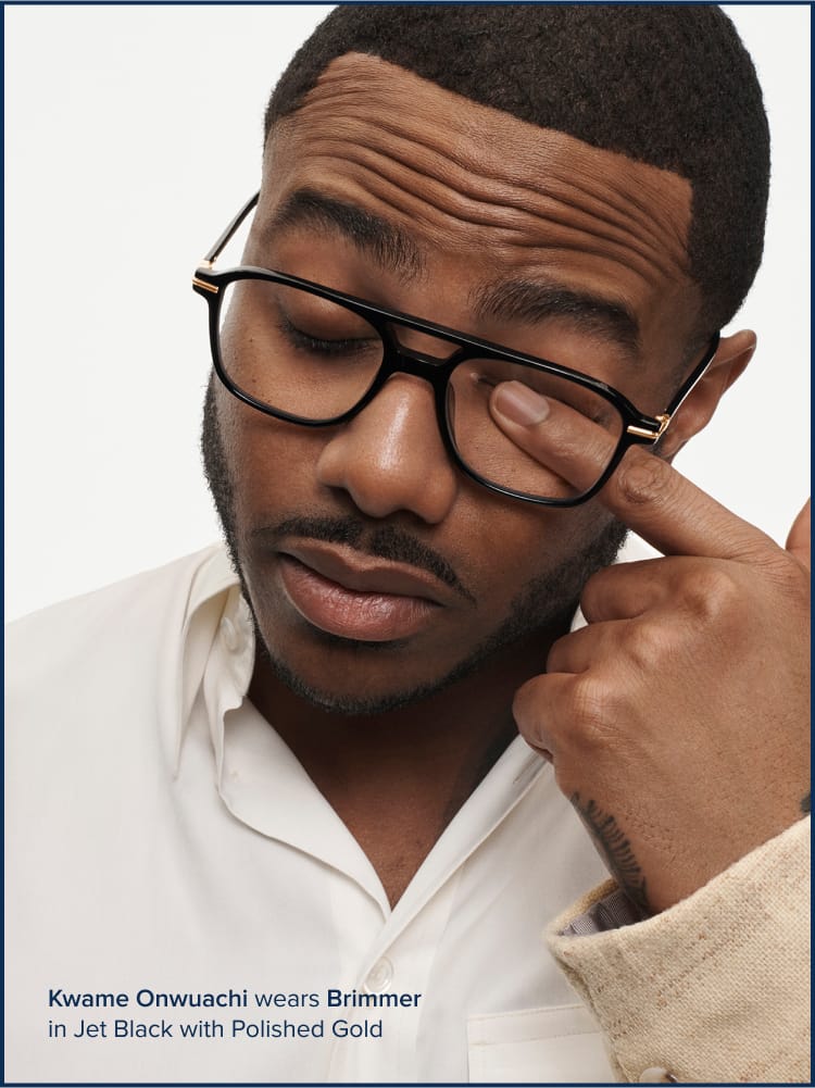 Person rubbing their eye through their eyeglasses.