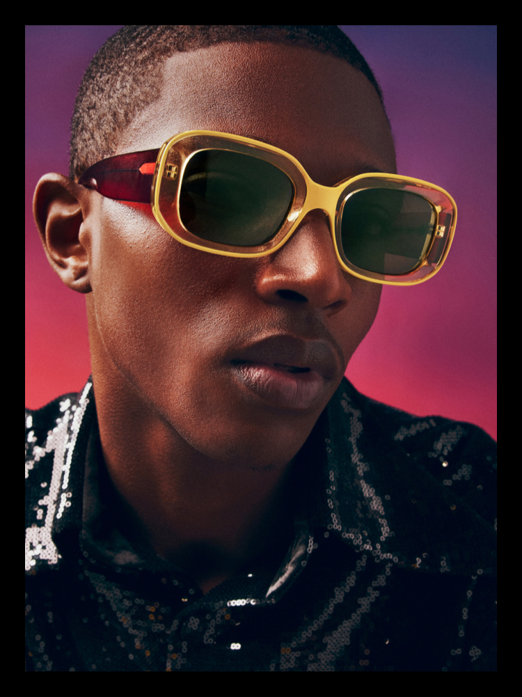 Person wearing glasses with looking at the camera against a red background.