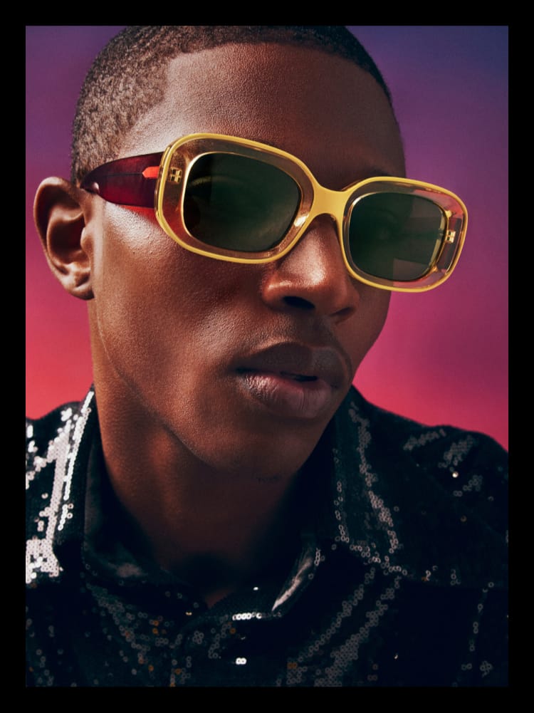 Person wearing glasses with looking at the camera against a red background.