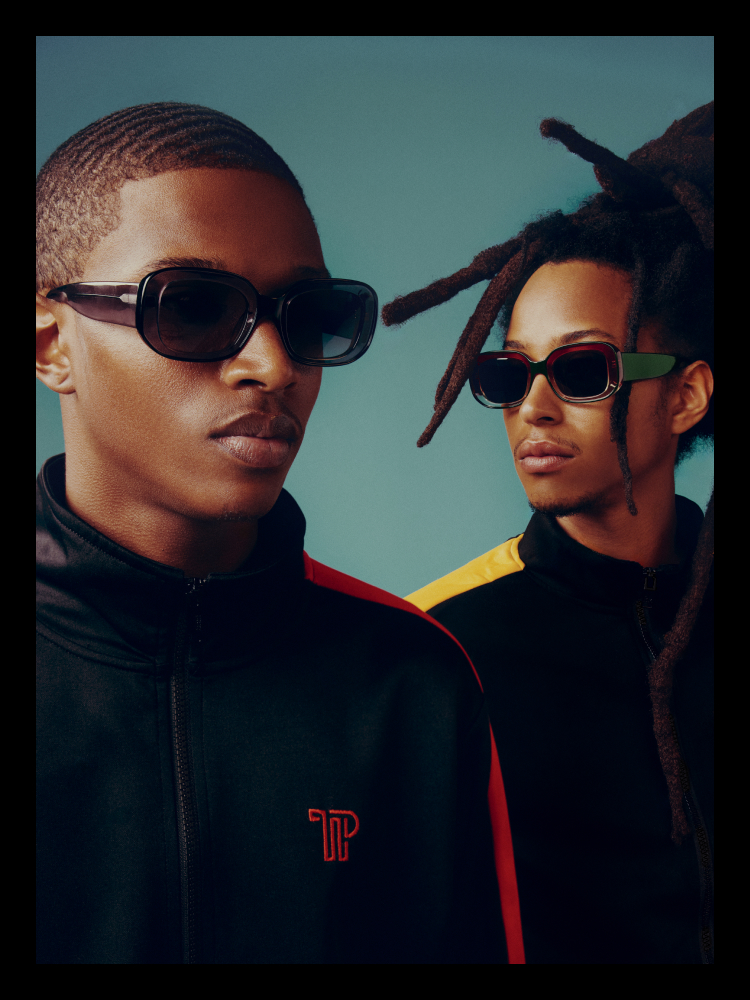 Two persons wearing sunglasses against a blue gradient background.