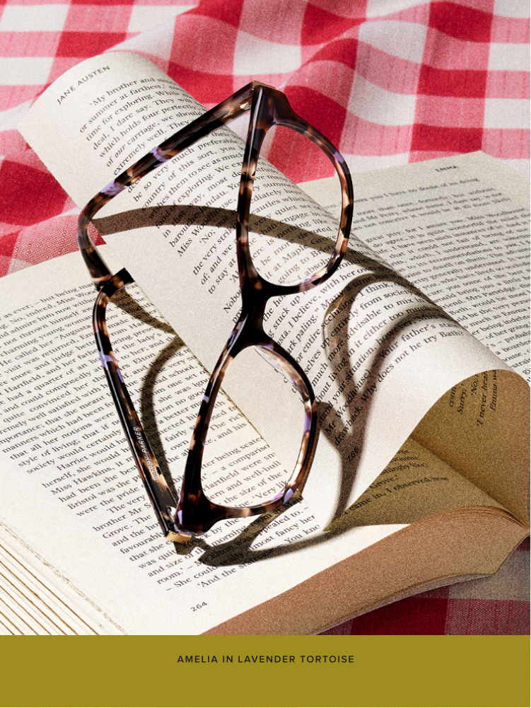The Amelia frame in Lavender Tortoise leans against an opened book.