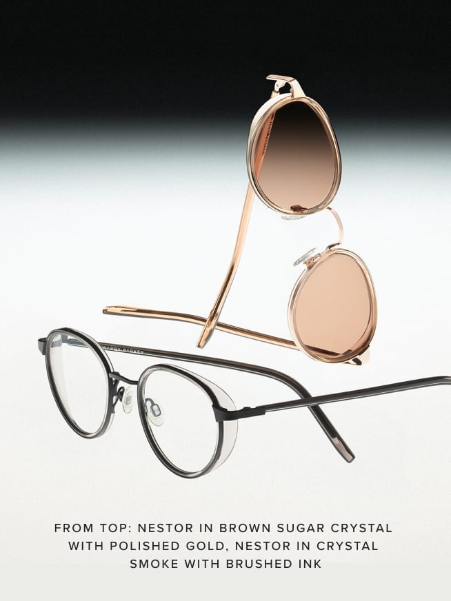 Two pairs of eyeglasses: the top pair is Nestor in Brown Sugar Crystal with Polished Gold, and the bottom pair is Nestor in Crystal Smoke with Brushed Ink.