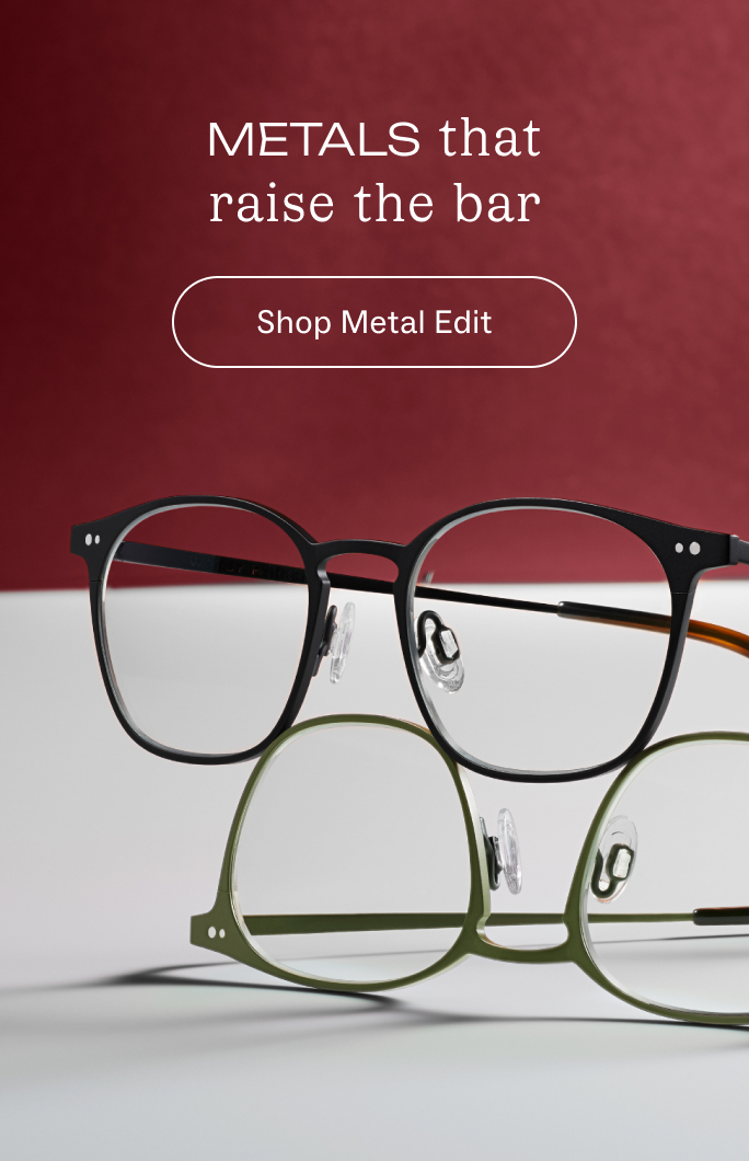Black metal eyeglasses with round lenses are displayed on a textured brown surface.