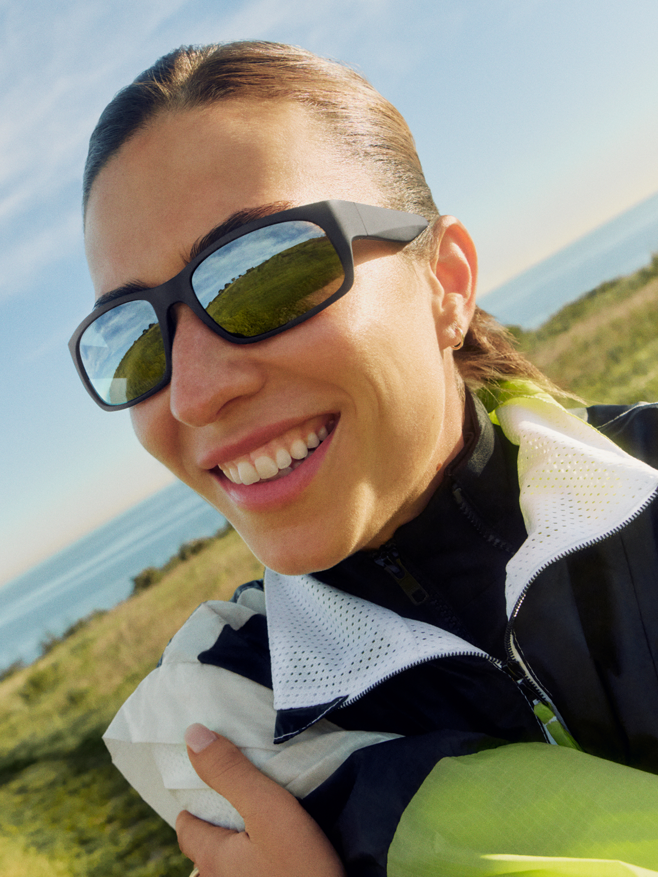 A man with sunglasses looks to the side against a bright blue sky.