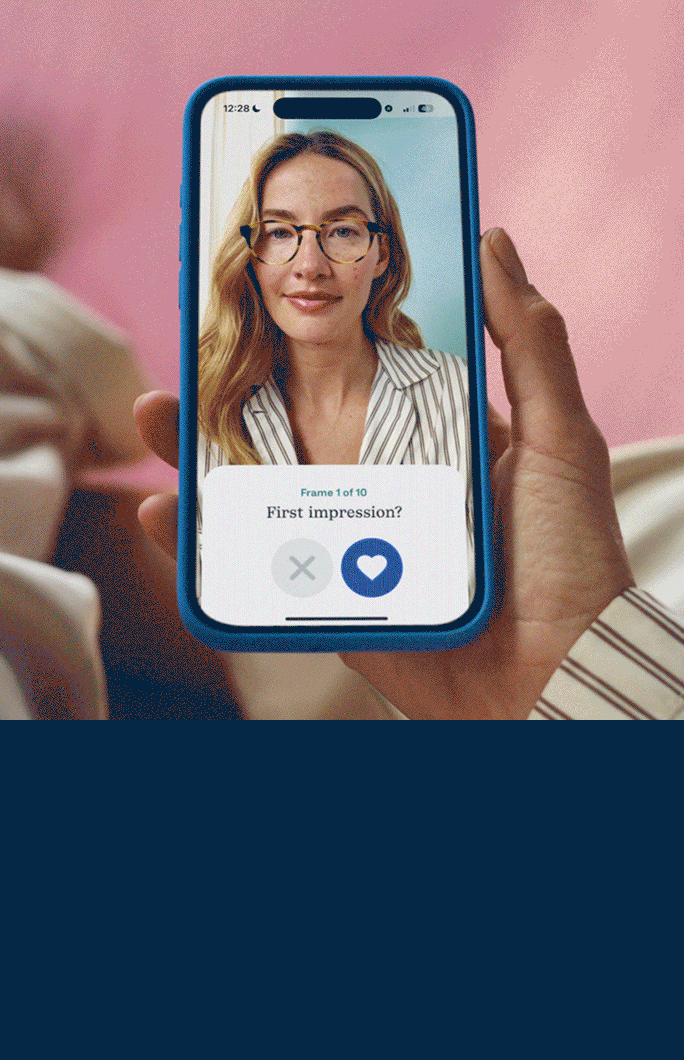 A hand holds a smartphone, displaying a profile picture of a person with green hair, glasses, and a heart icon.