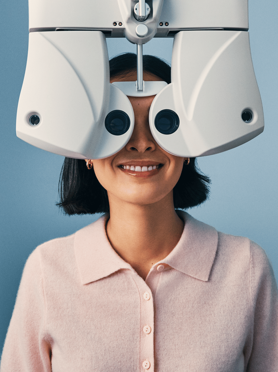 A woman is having her eyes examined using a phoropter at an optometrist's office.