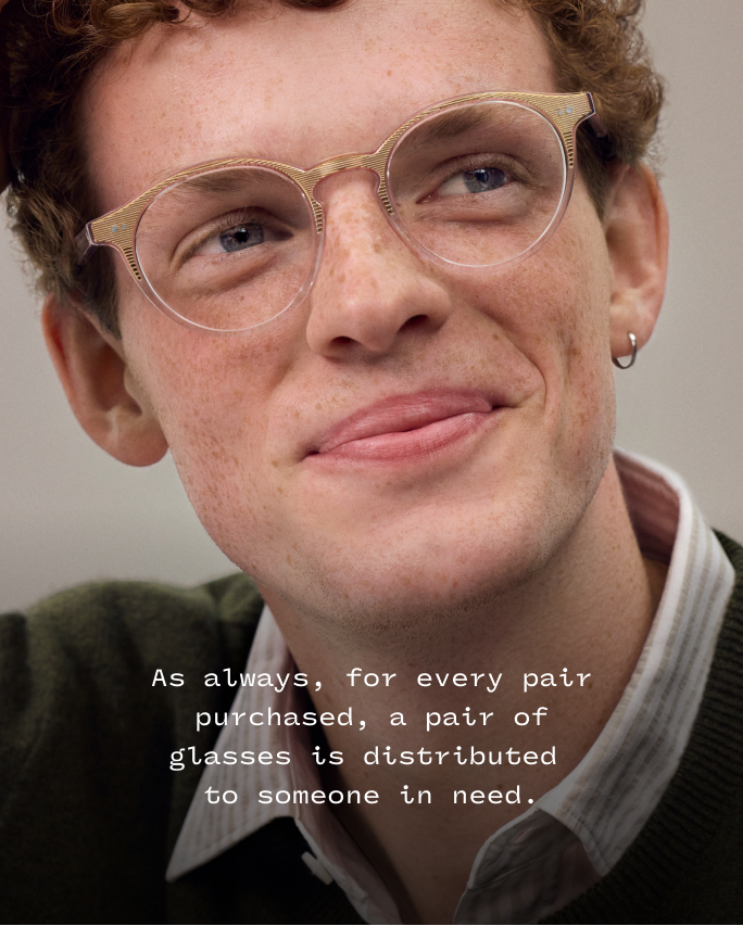 Smiling person wearing translucent glasses, with text about buying one pair and giving one pair.