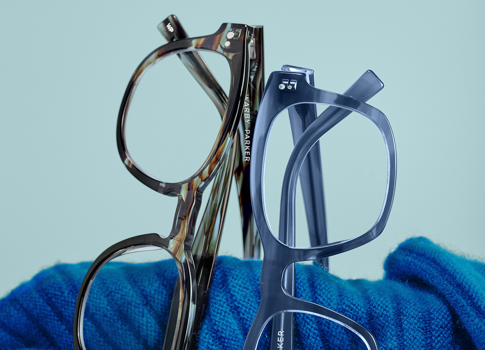 Two frames resting on top of a blue cloth and blue background