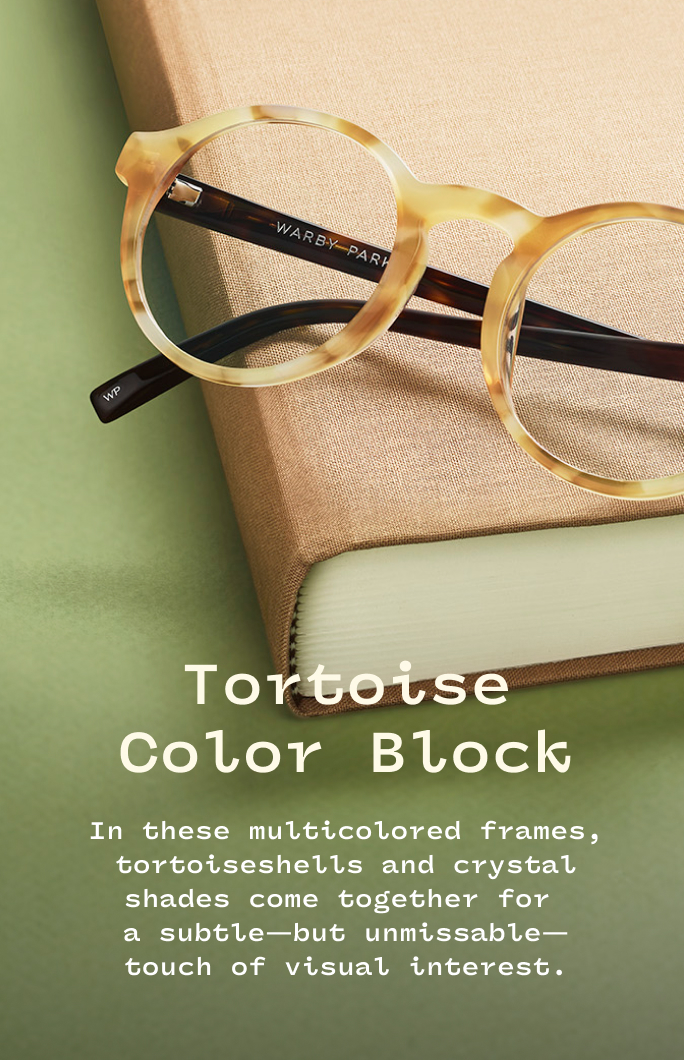 Tortoiseshell and crystal-colored eyeglass frames resting on a beige book.