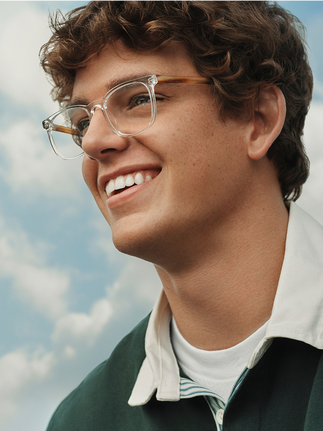 Close-up of a young man with curly hair and tortoiseshell glasses looking right.