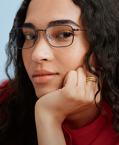A close-up shot of black-rimmed eyeglasses, with one lens and part of the frame in sharp focus.