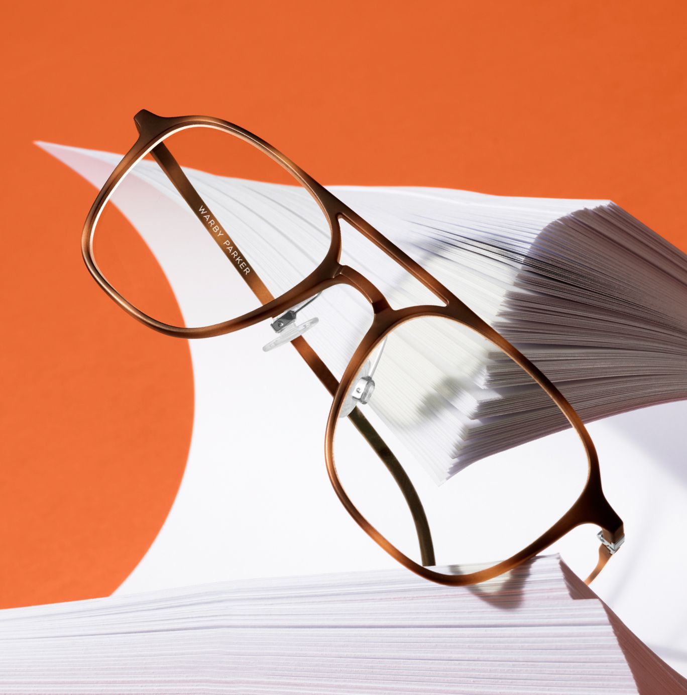 A pair of black eyeglasses with tortoise shell temples rests atop a pair of black sunglasses.