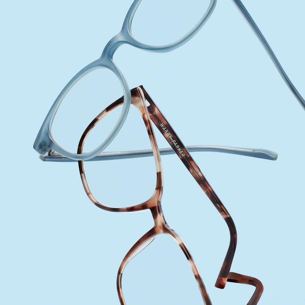 Two pairs of glasses, one light blue and one tortoiseshell, overlap on a blue background.