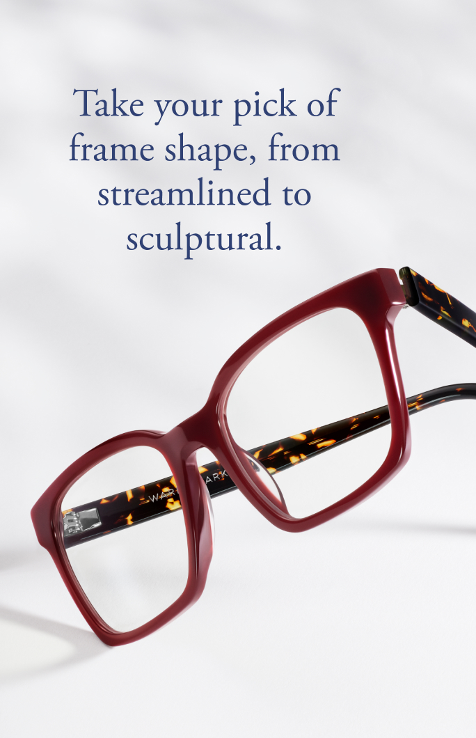 A pair of maroon eyeglasses with a tortoiseshell pattern on the arms rests on a white surface.