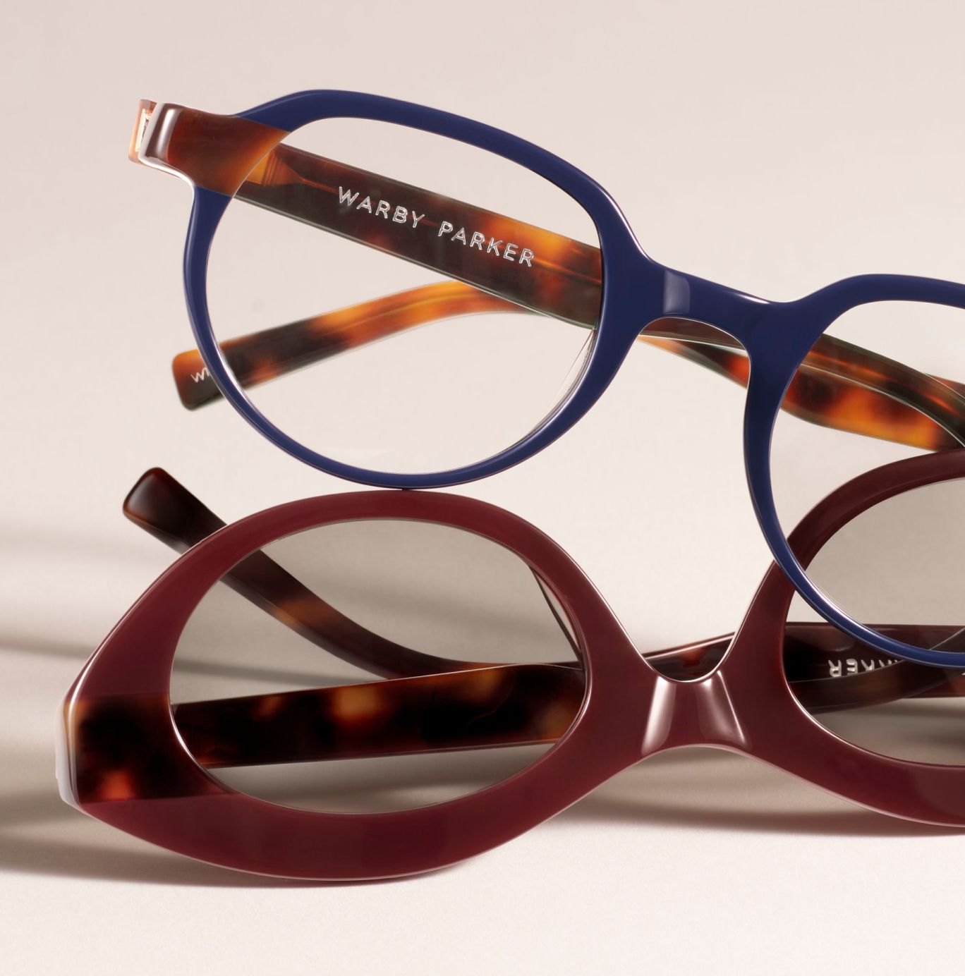 A bald man carrying a woman on his back. Both are wearing sunglasses and smiling.