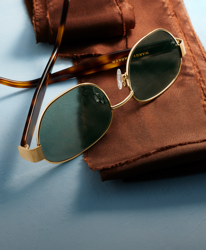 Two pairs of Warby Parker glasses, one with green lenses, the other with clear lenses.