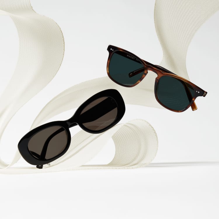 Two pairs of sunglasses, one with black oval frames and the other with tortoiseshell rectangular frames, displayed against a textured cream background.