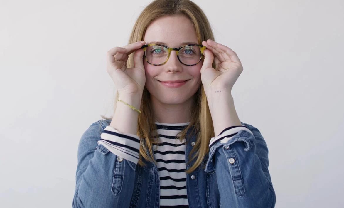 Woman placing the finished frame on their face and smiling with the results.