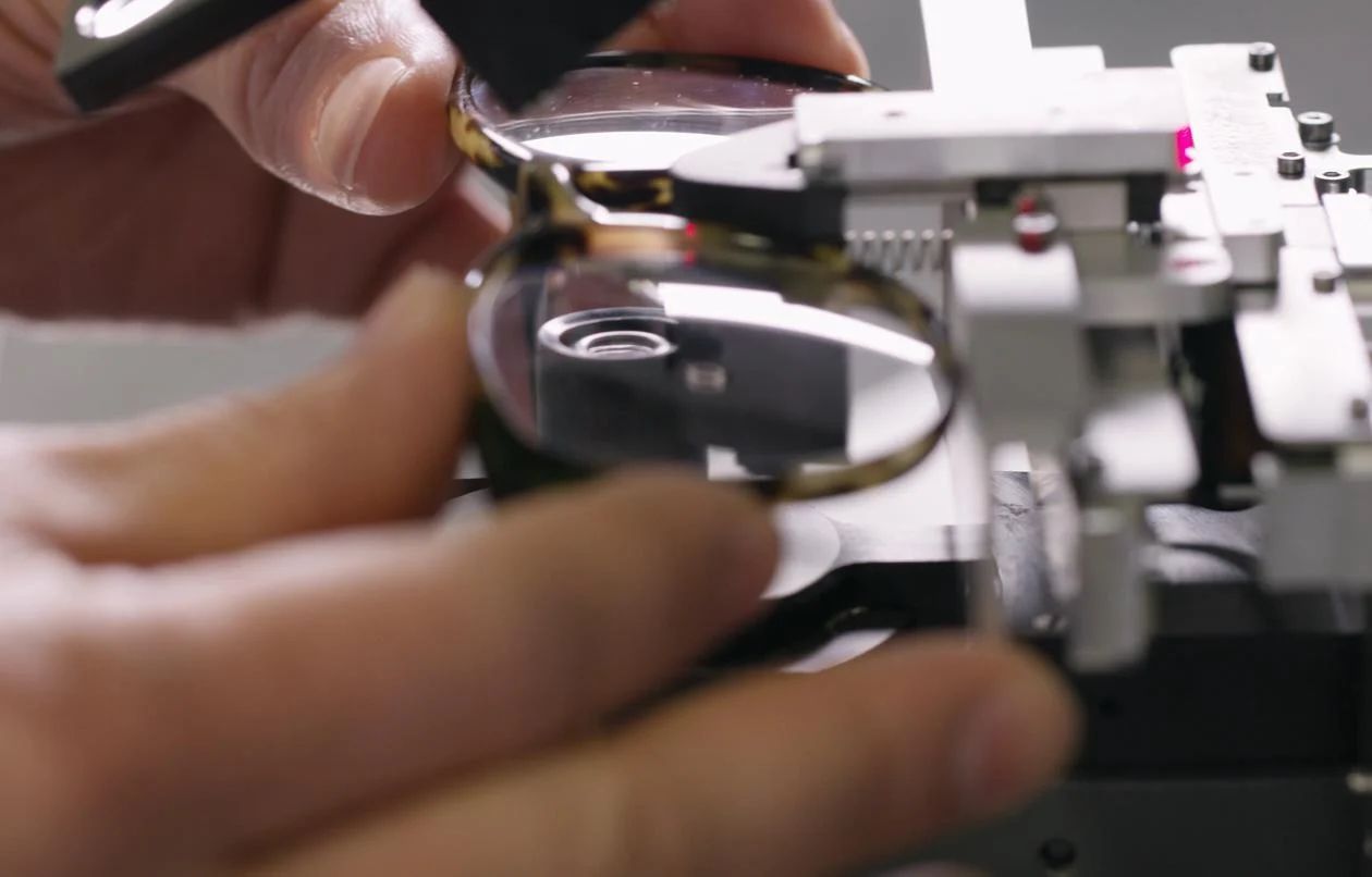 Frames being held into a machine for lenses to go through a final review, where the prescription is checked one last time