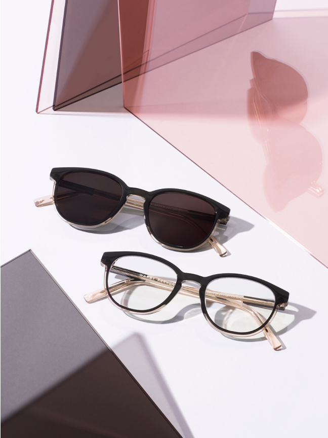 One eyeglass and one sunglass resting on a between some glasses.