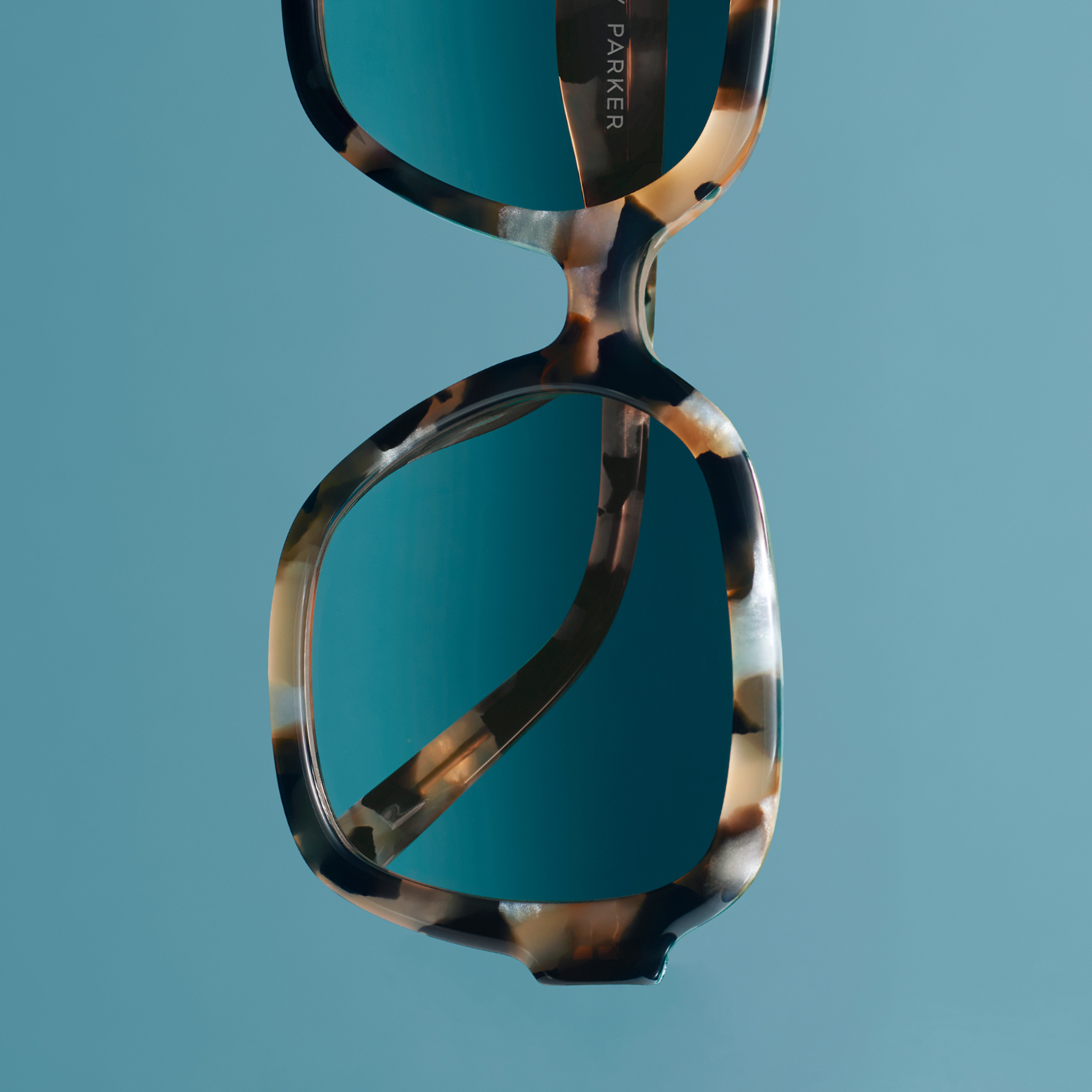 Warby Parker Winter 2024 Sunglasses gloating against a blue background.