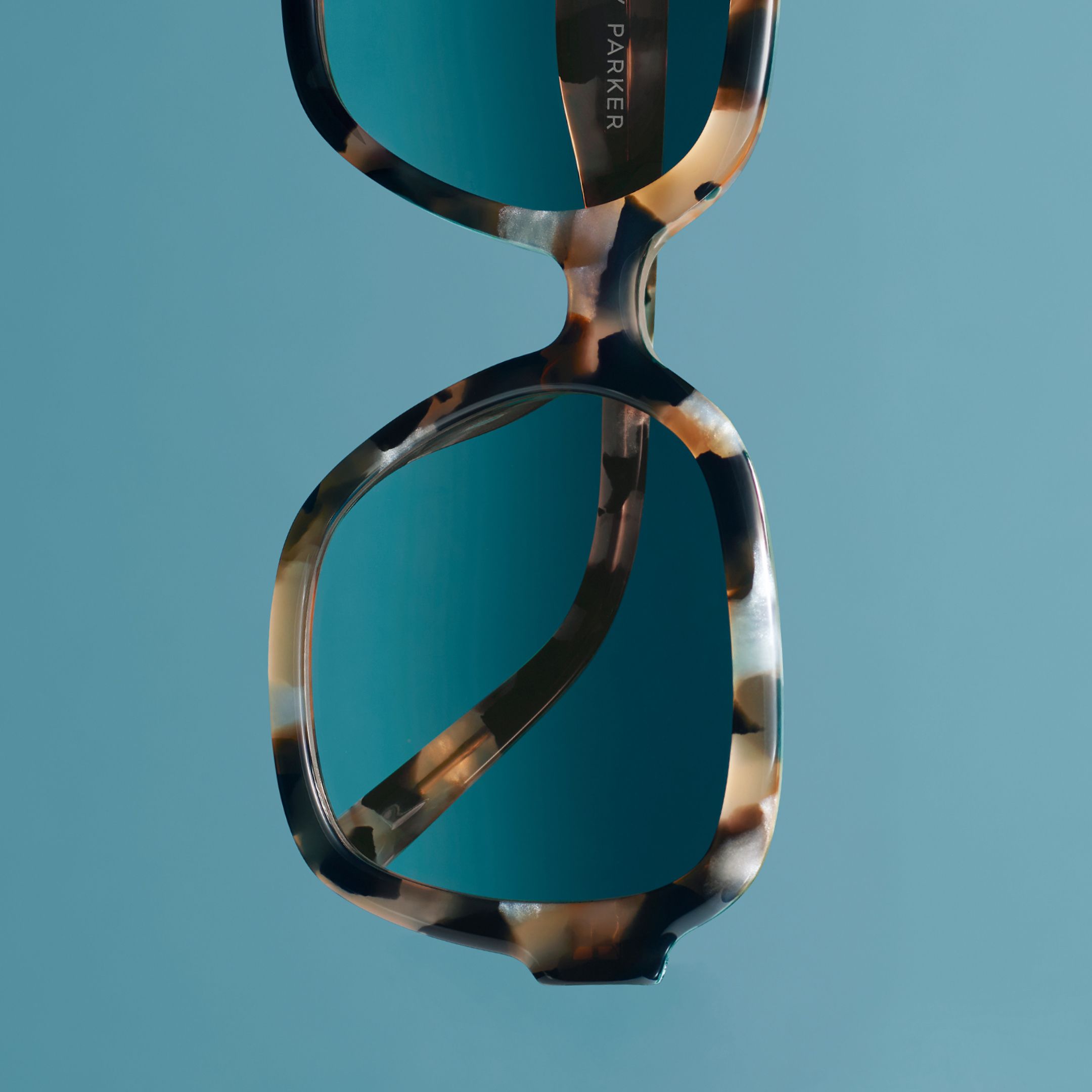 Warby Parker Winter 2024 Sunglasses gloating against a blue background.