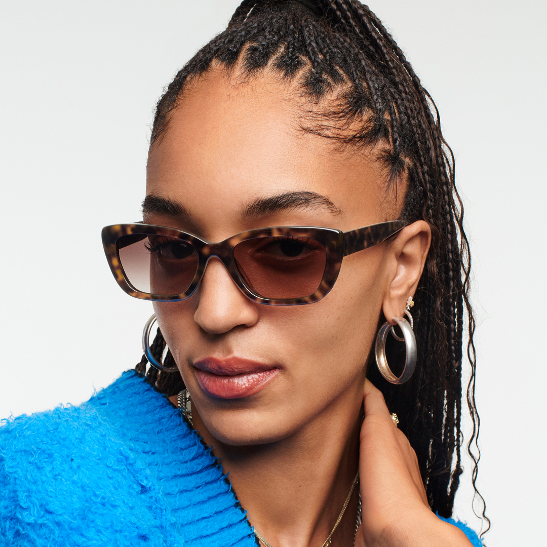 Woman with sunglasses looking at the camera with the hand on the neck.