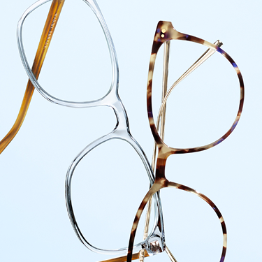 Two pairs of eyeglasses on a light background.