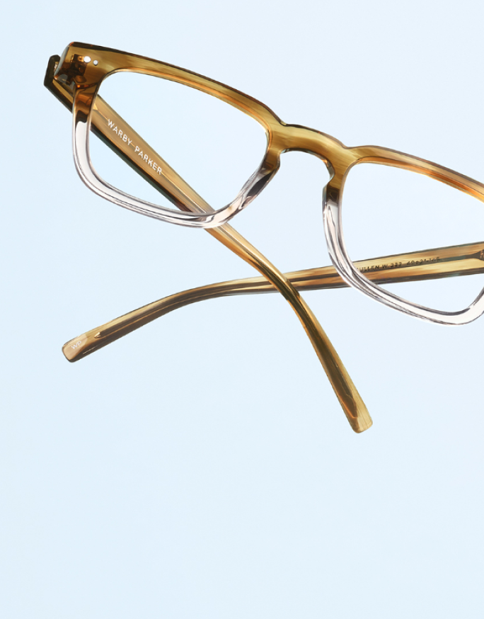 Eyeglass prescription slip on a desk, with open books in the background.