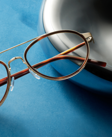 Tortoiseshell glasses with gold trim and clear lenses rest on a blue surface.