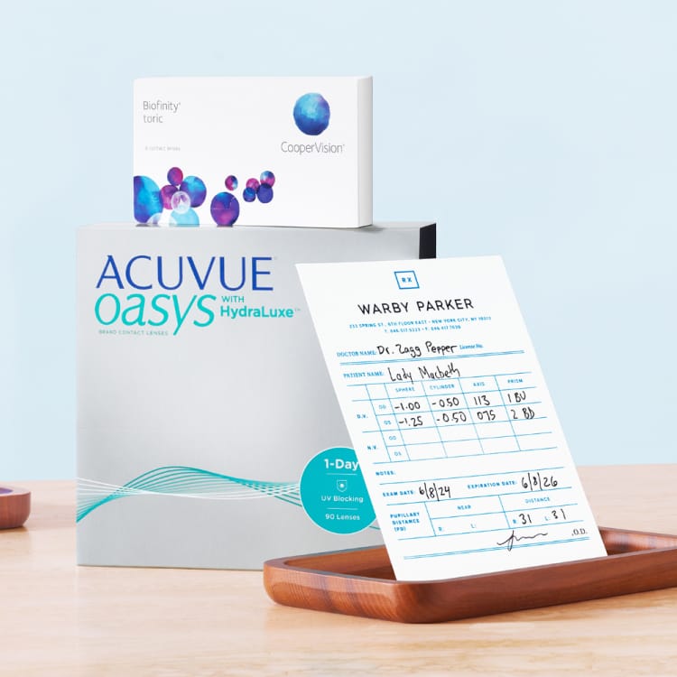 Image of Scout contacts by Warby Parker. Three flat compact packages in bright blue, dark blue, and light grey blue that carry individual Scout contacts for daily use.