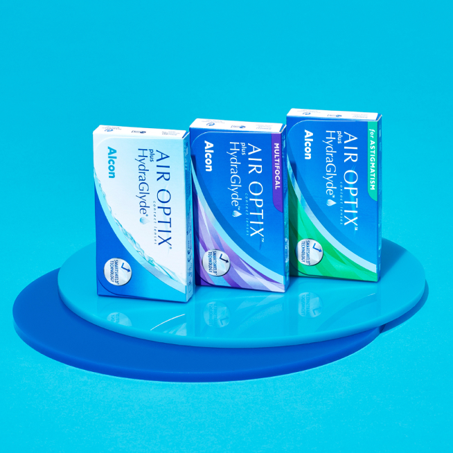Three boxes of Alcon Air Optix contact lenses on blue circular platforms.