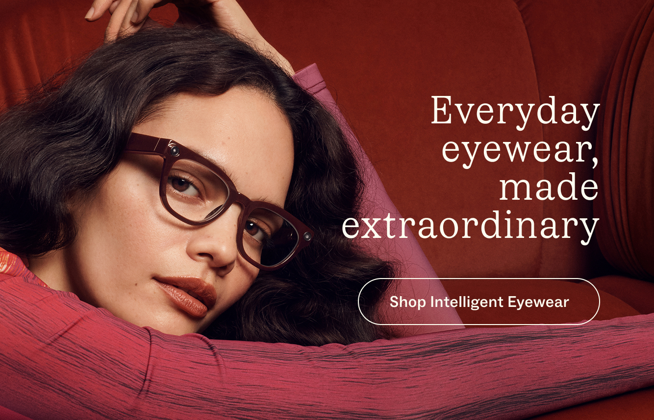 A woman wearing stylish glasses is shown in a close-up shot on a plush couch. The text says "Everyday eyewear, made extraordinary."