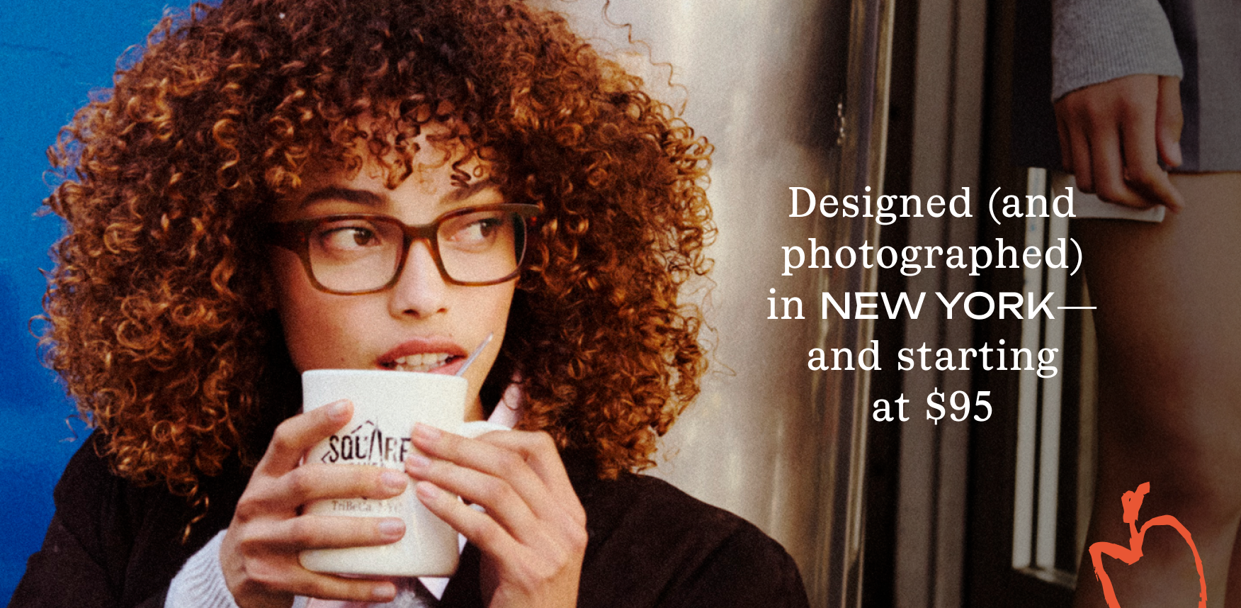 A young woman with curly brown hair and glasses drinks from a mug.
