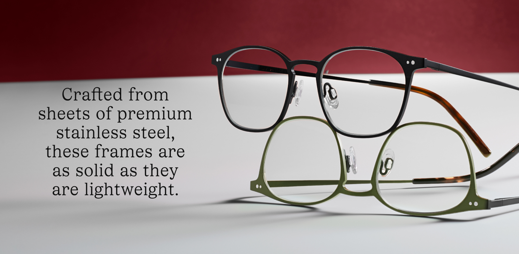Two pairs of glasses, one black and one olive green, are stacked on top of each other.