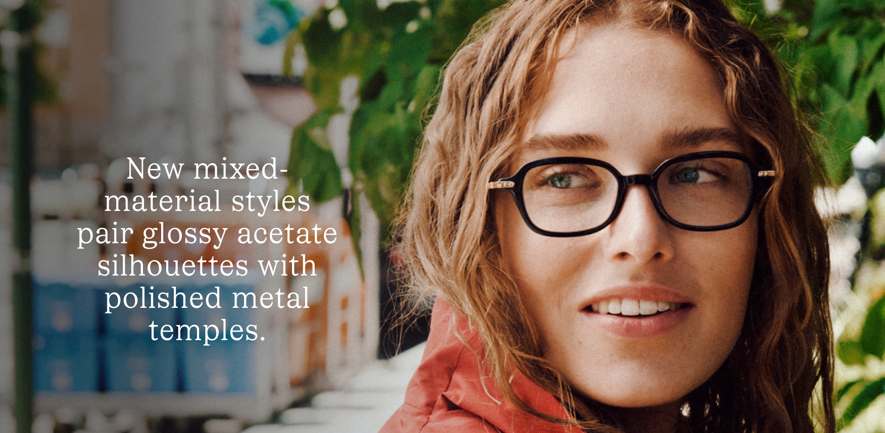 A woman wears black square glasses with metal temples. Text reads: New mixed-material styles pair glossy acetate silhouettes with polished metal temples.